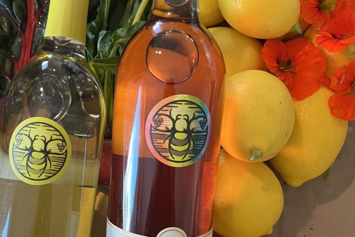 A bottle of Eco Terreno Sauvignon Blanc, and Pink Pride Rose with lemons in the background.